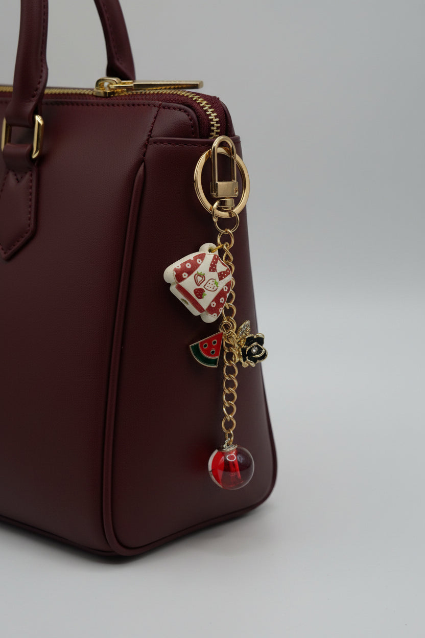 Strawberry dress charm keychain with watermelon slice, black rose charm, and red orb bead on gold chain
