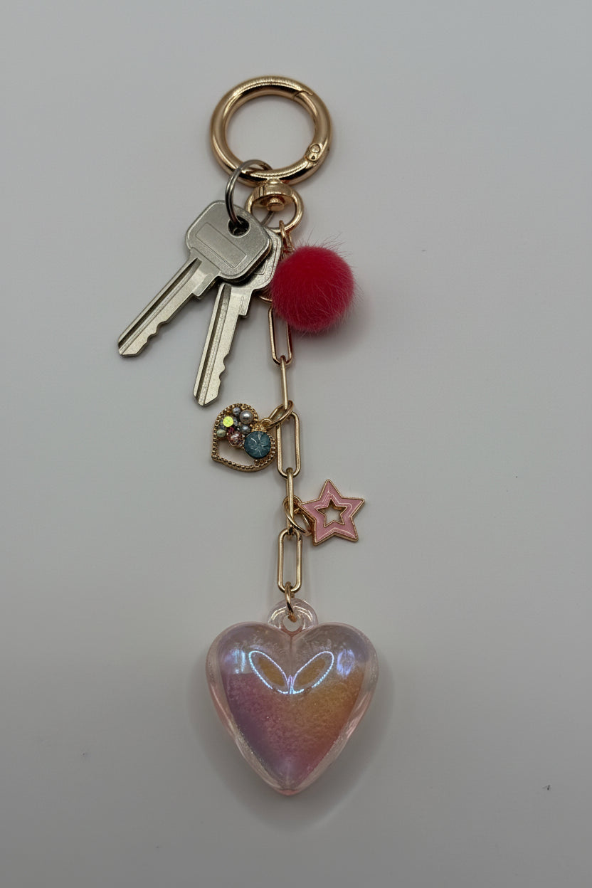 Iridescent holographic heart charm keychain with red pom-pom, rhinestone heart, and pink star charm on gold paperclip chain