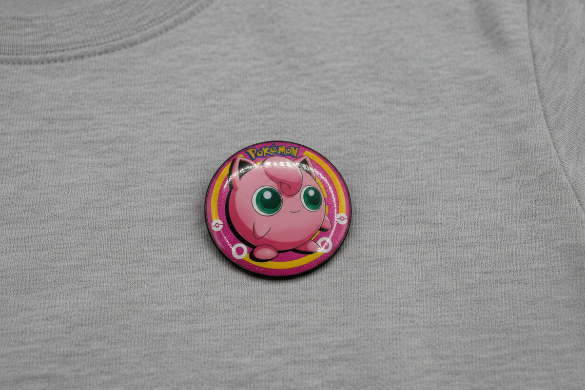 Pokémon Jigglypuff button pin and matching collectible card set on white background