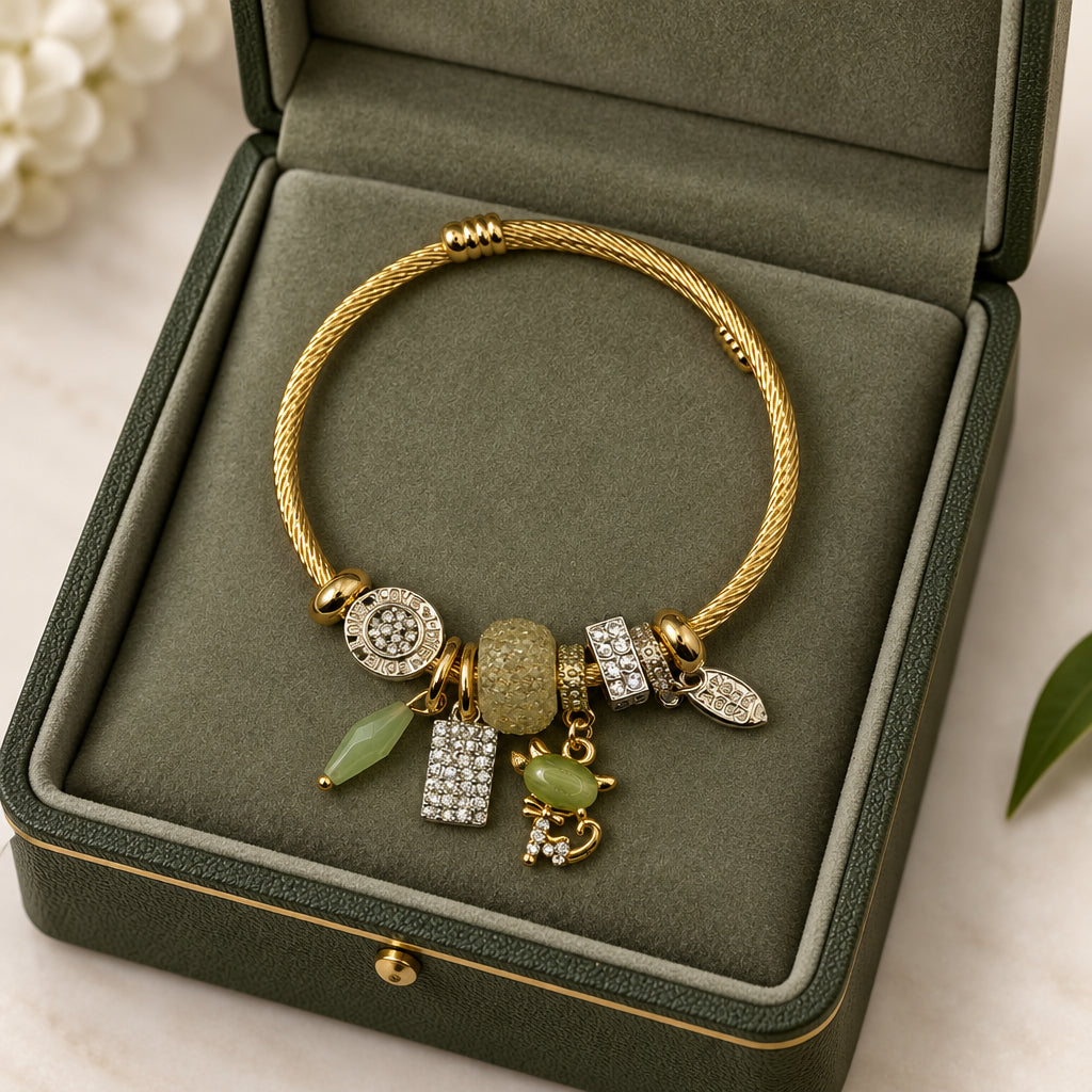 Gold twisted cable charm bangle bracelet with green jade bead, cat charm, and crystal accents