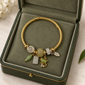 Gold twisted cable charm bangle bracelet with green jade bead, cat charm, and crystal accents