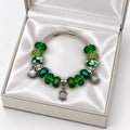 Silver twisted wire bangle bracelet with green crystal beads, rhinestone pave beads, murano glass beads, and silver turtle and shell charms