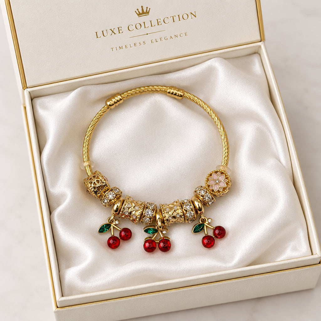 Gold twisted cable charm bangle bracelet with red enamel cherry charms, gold filigree beads, and white flower accent