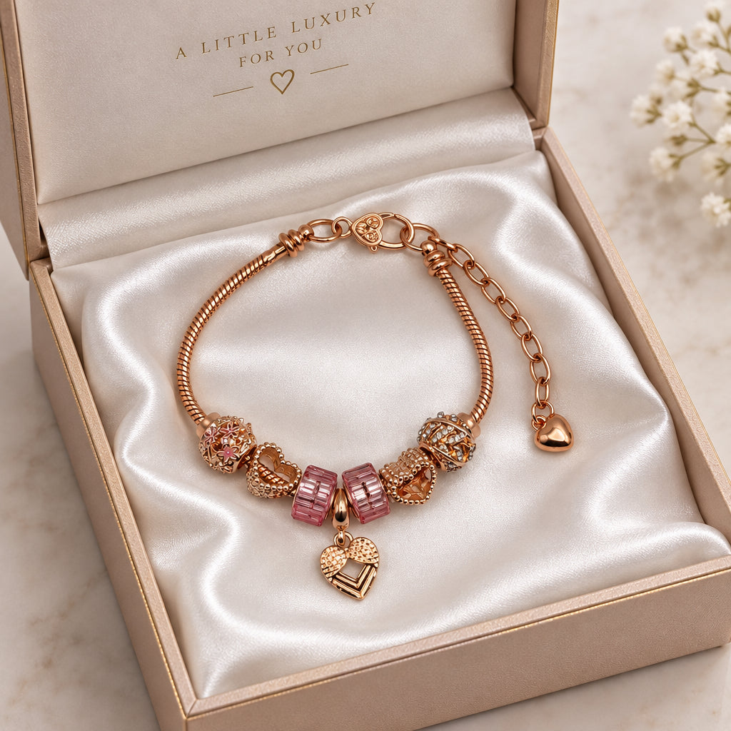 Rose gold snake chain bracelet with pink crystal cube beads, filigree metal charms, and dangling heart pendant