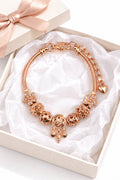 Rose gold snake chain bracelet with filigree beads, daisy flower charms, and dangling owl dreamcatcher pendant