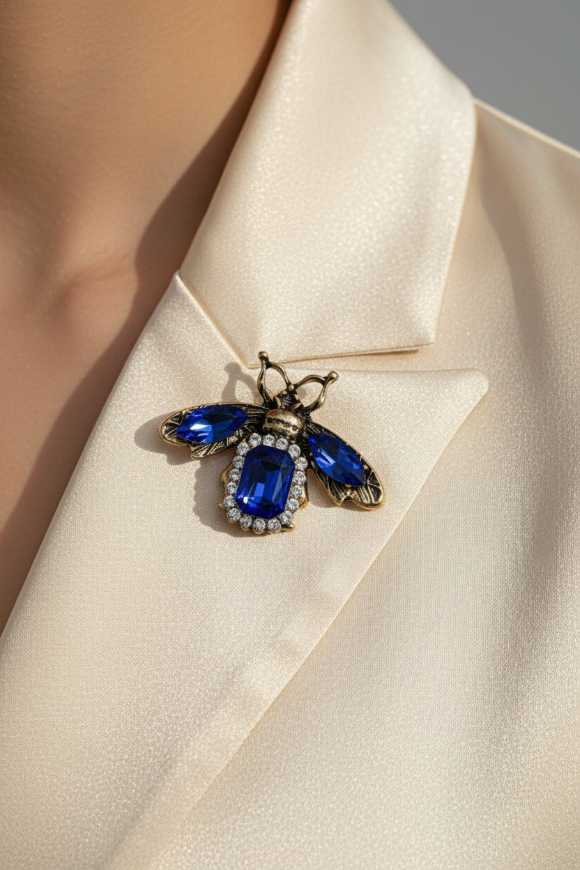 Blue sapphire crystal bee brooch with white rhinestone accents on display card