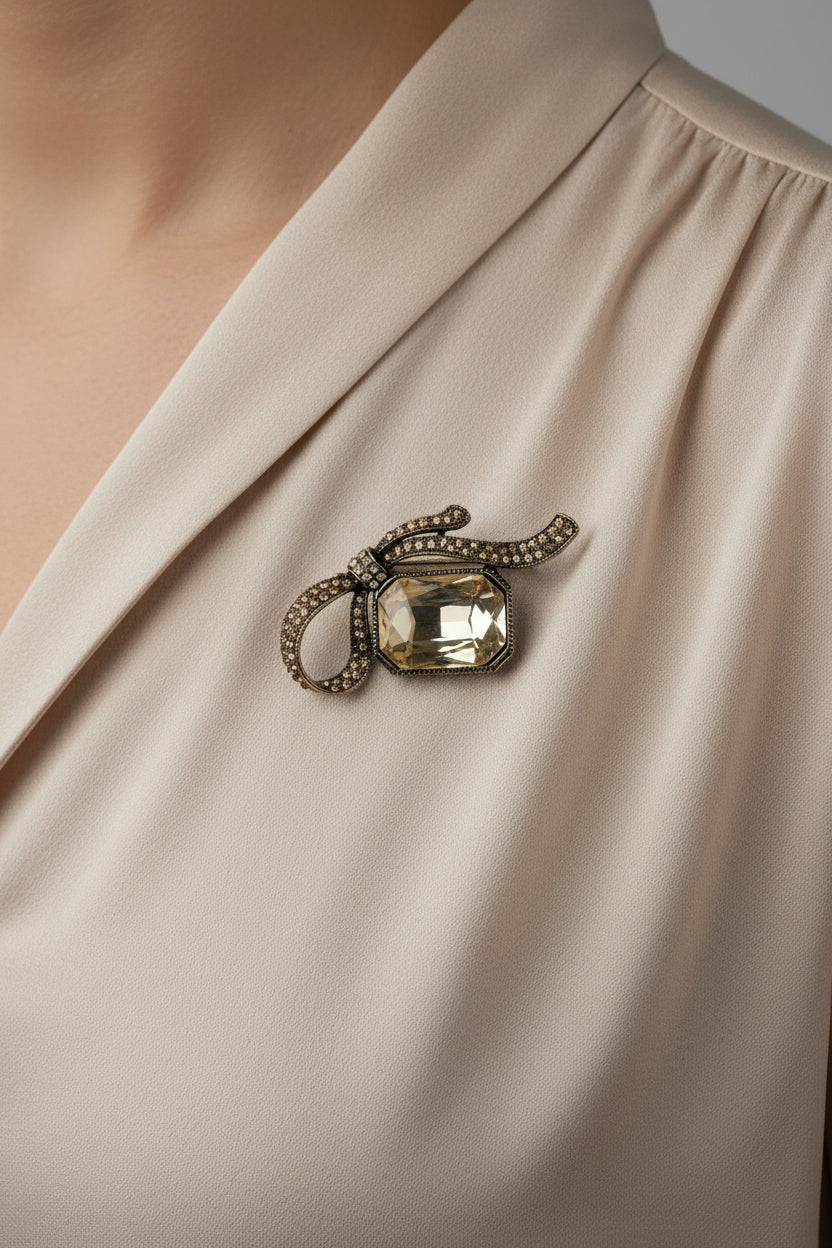 Champagne crystal bow brooch with large faceted gemstone center on display card