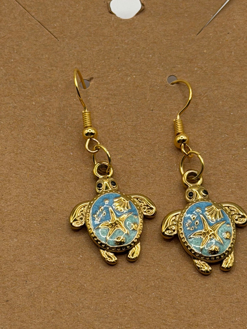 Gold sea turtle dangle earrings with blue enamel shell and starfish design on gold fish hook backs