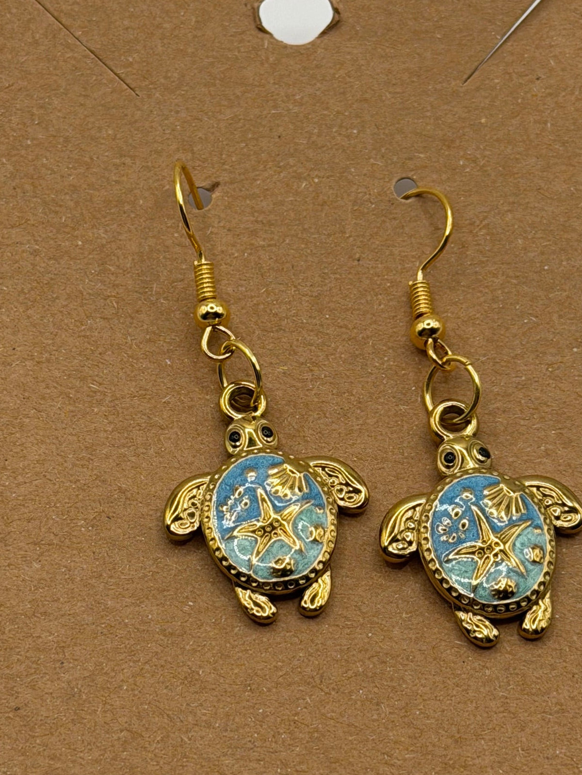 Gold sea turtle dangle earrings with blue enamel shell and starfish design on gold fish hook backs