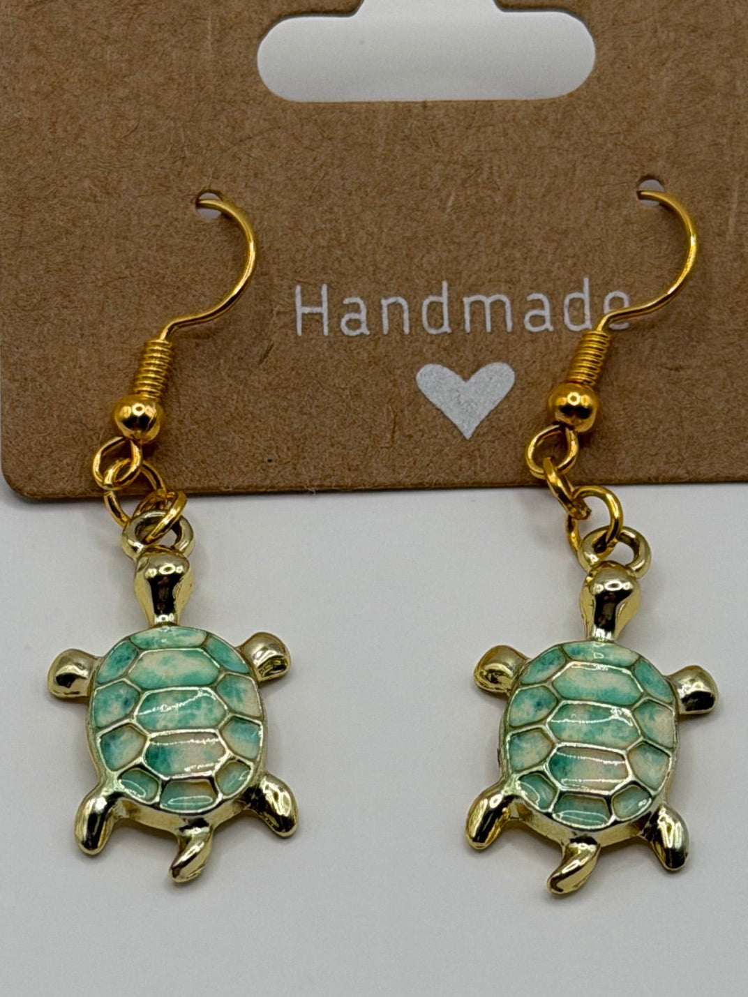 Handmade gold sea turtle dangle earrings with mint green enamel shell and gold fish hook backs