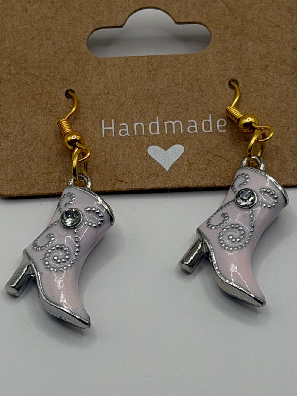 Handmade pink cowboy boot dangle earrings with silver swirl detail and rhinestone accent on gold fish hook backs