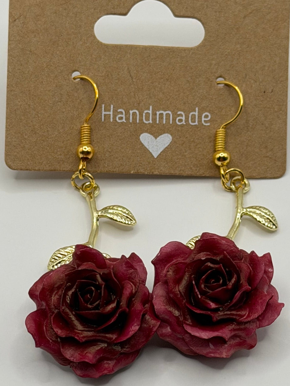 Handmade burgundy rose dangle earrings with gold-tone stem and leaf detail on gold fish hook backs