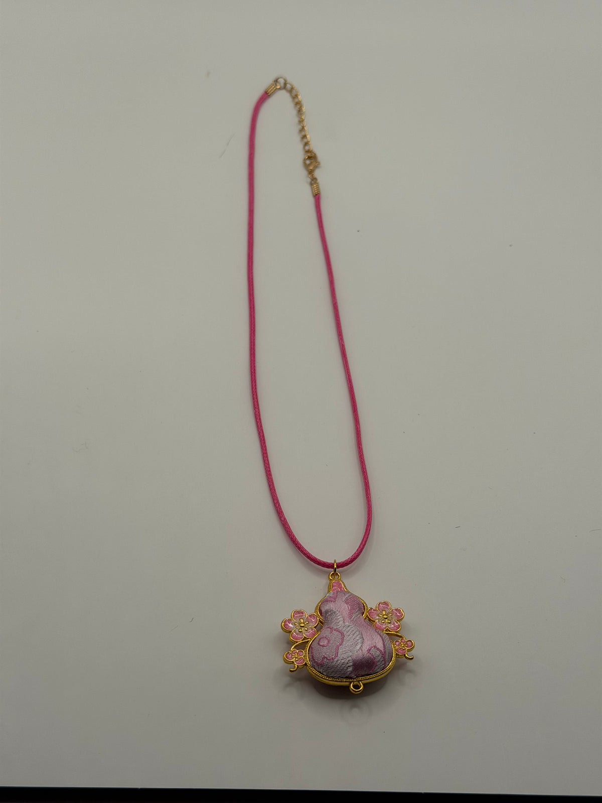 Handmade hot pink cord necklace with lavender gourd-shaped pendant in gold filigree frame with pink enamel cherry blossom accents