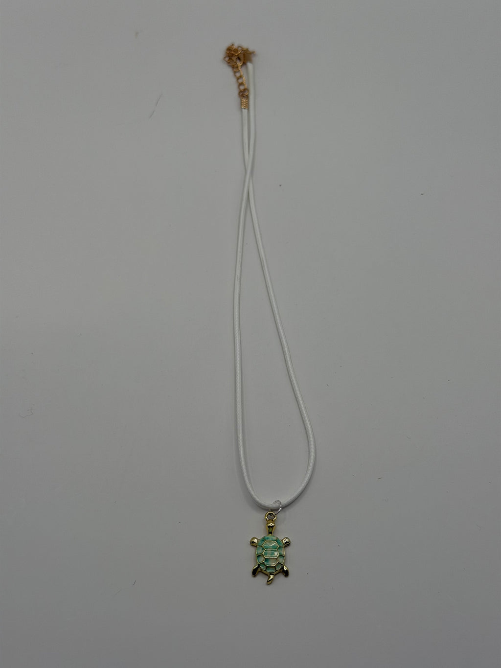 Handmade white double cord necklace with gold and green enamel sea turtle charm and gold adjustable extender chain