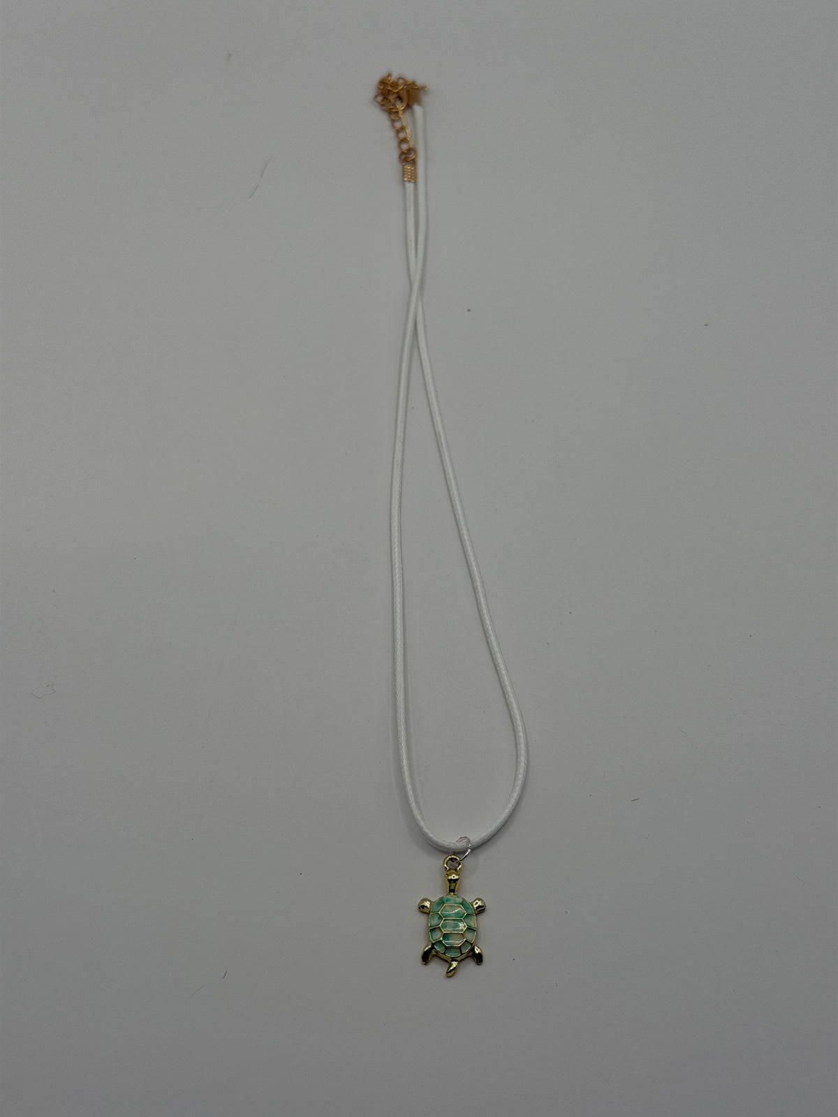 Handmade white double cord necklace with gold and green enamel sea turtle charm and gold adjustable extender chain