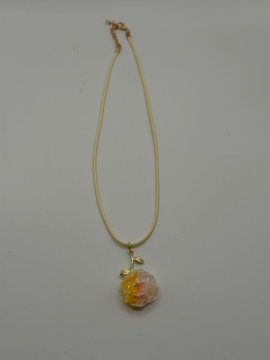 Handmade cream cord necklace with pink and yellow resin peony flower pendant and gold leaf accent