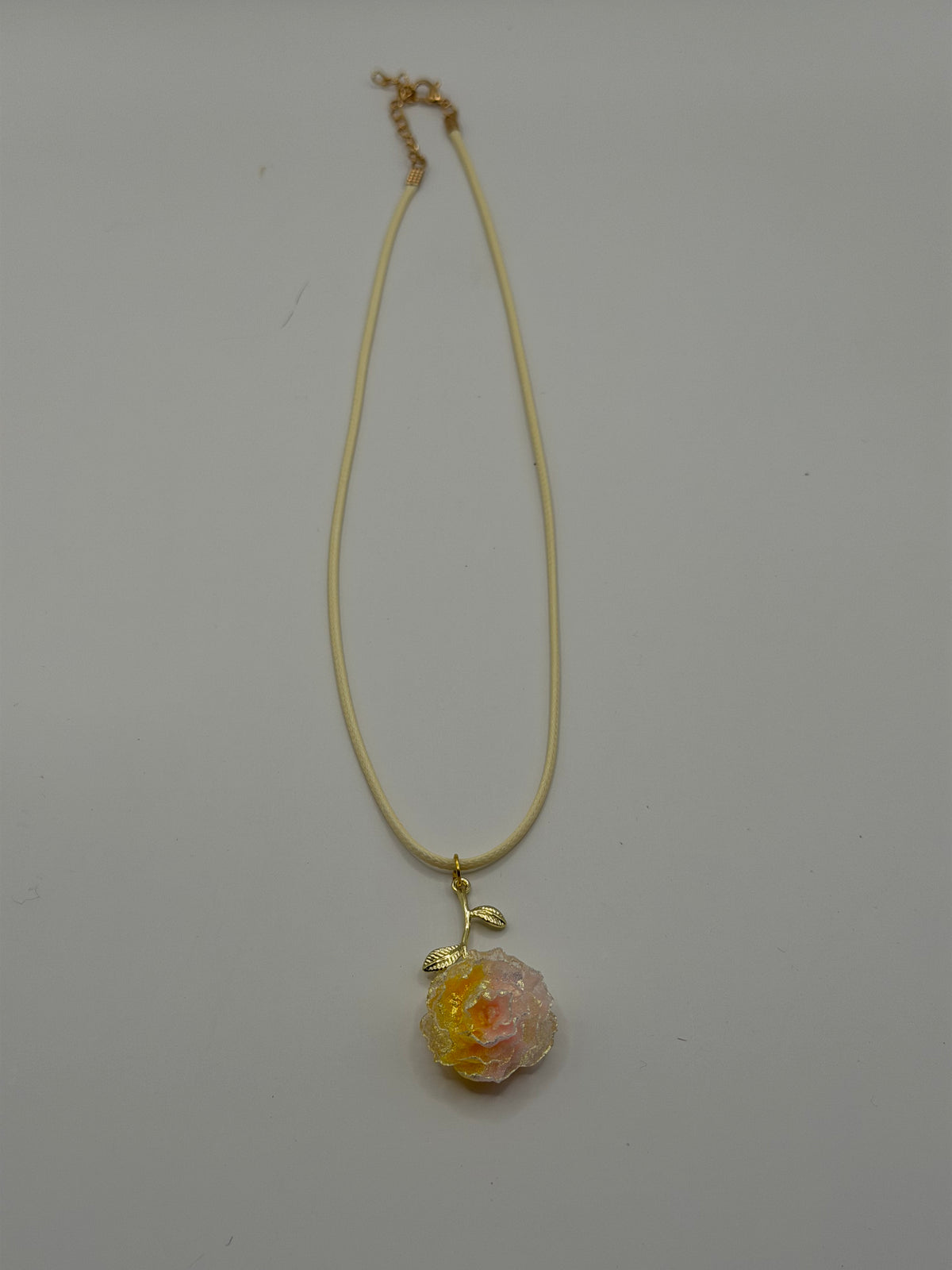 Handmade cream cord necklace with pink and yellow resin peony flower pendant and gold leaf accent