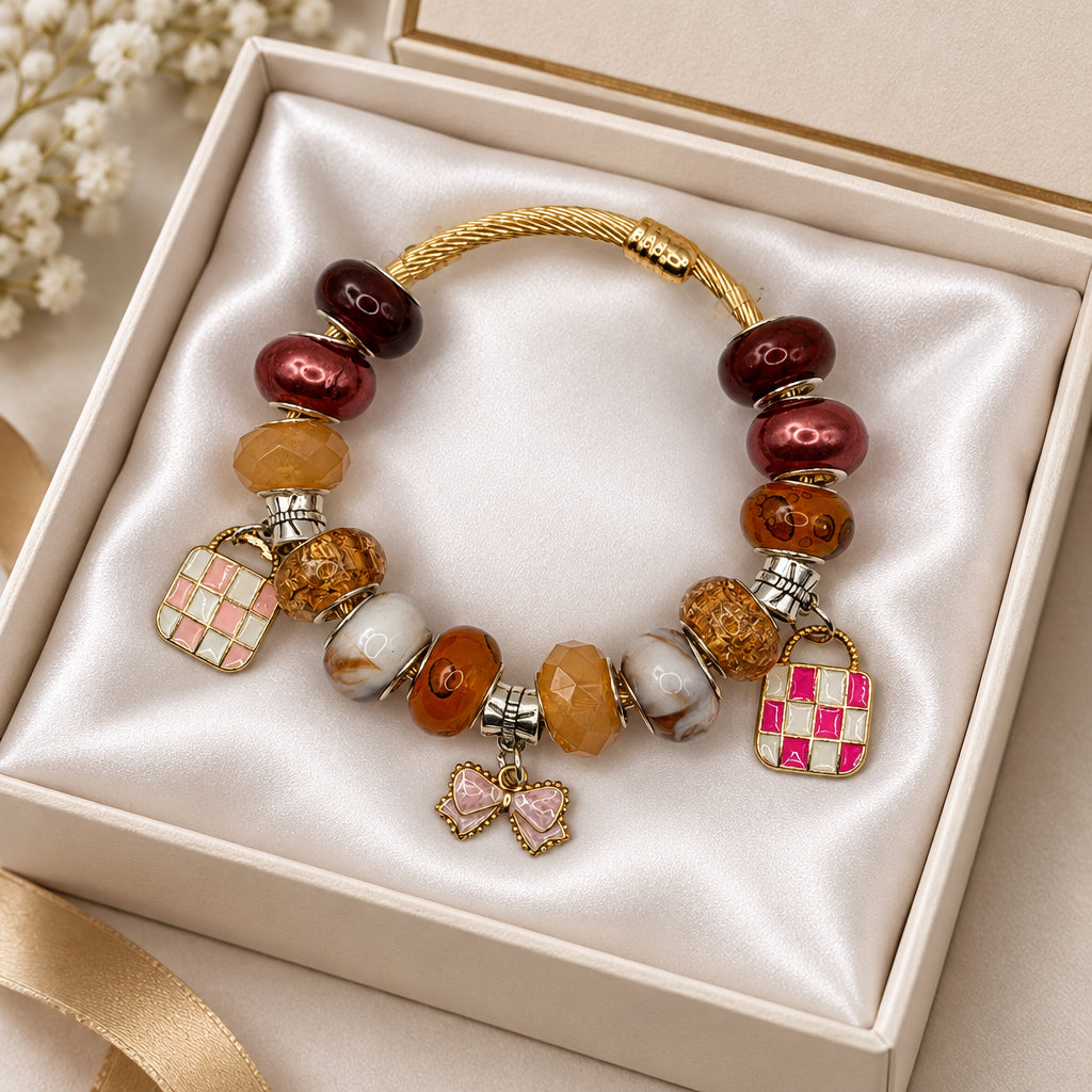 Gold twisted cable charm bangle bracelet with brown and burgundy beads, enamel handbag charms, and pink bow charm