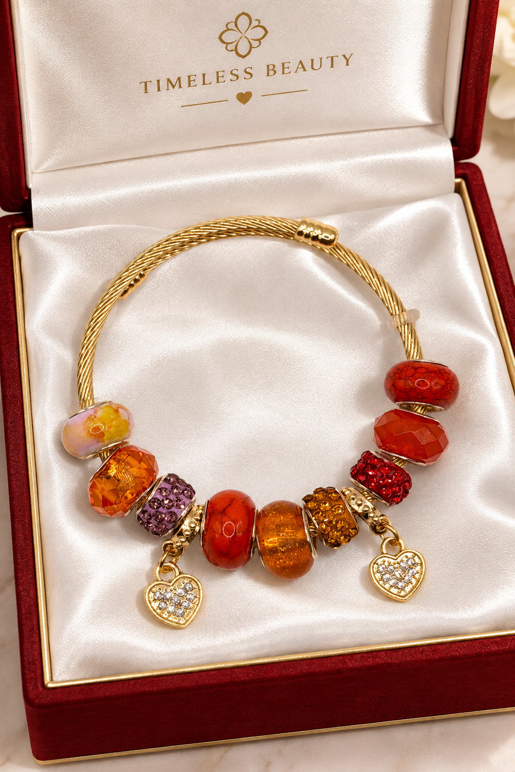 Gold twisted cable charm bangle bracelet with orange and amber beads and rhinestone heart charms