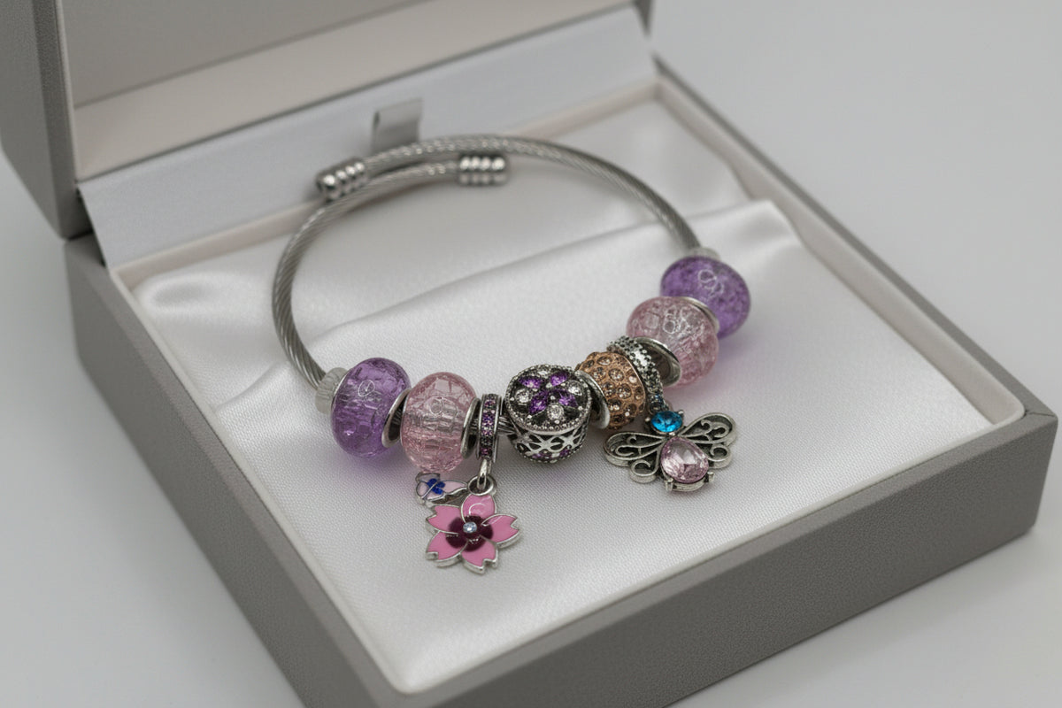Silver twisted cable charm bangle bracelet with purple and pink beads, pink flower charm, and silver butterfly charm with blue crystal