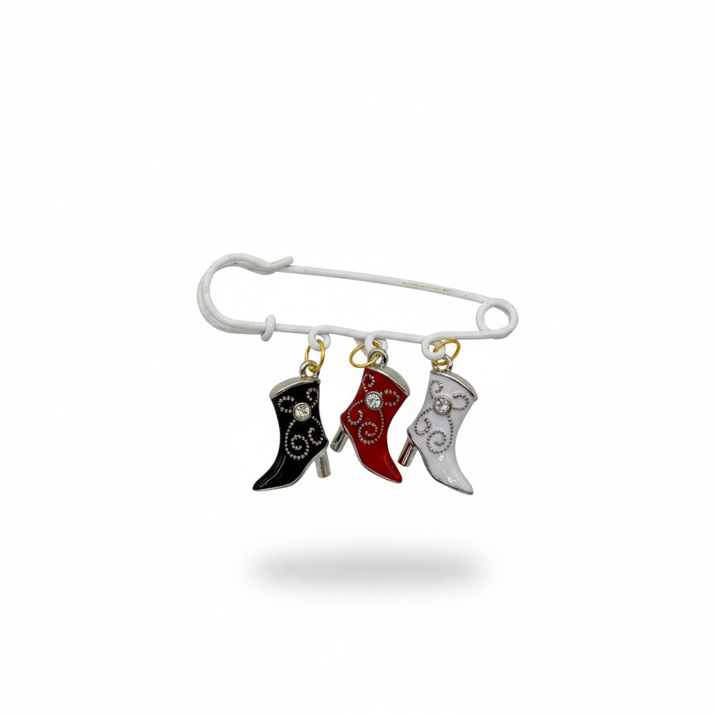 Handmade white safety pin with black, red, and white enamel cowboy boot charms on a kraft Handmade display card