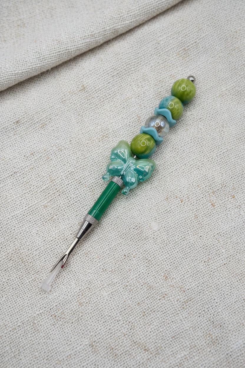 Teal seam ripper with butterfly charm and olive green beaded handle
